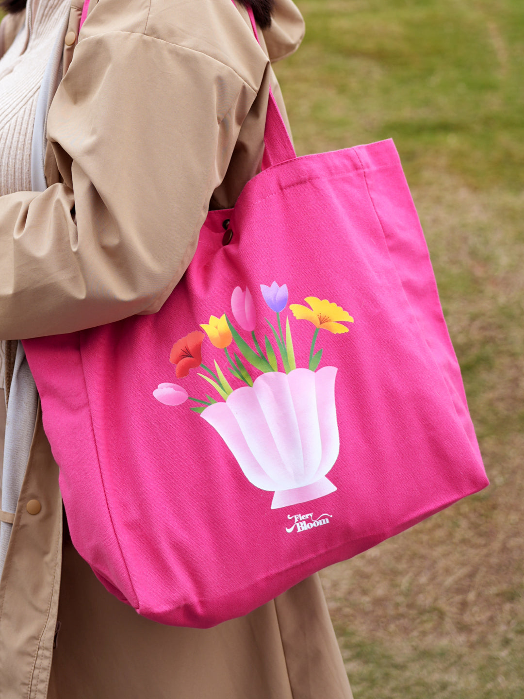 Model carrying a Fiery Bloom pink floral tote bag made of eco-friendly cotton canvas.