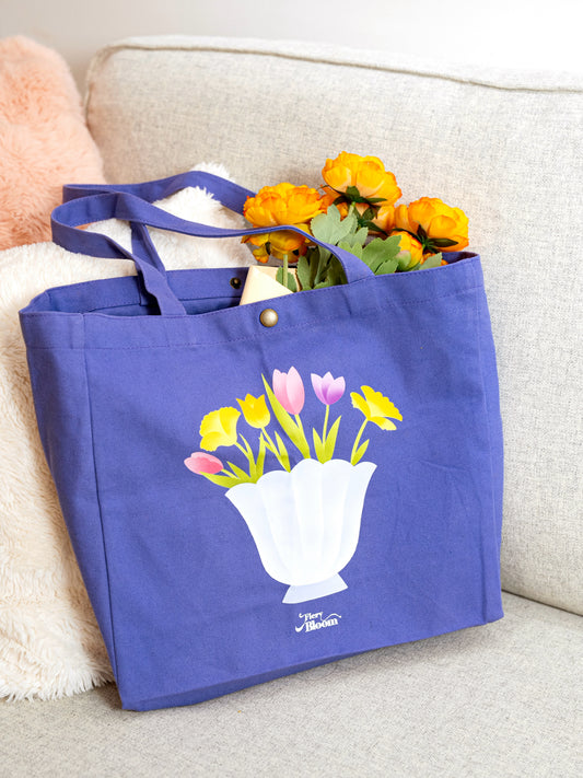 Close-up of the stitching and vibrant floral artwork on a purple cotton canvas bag.